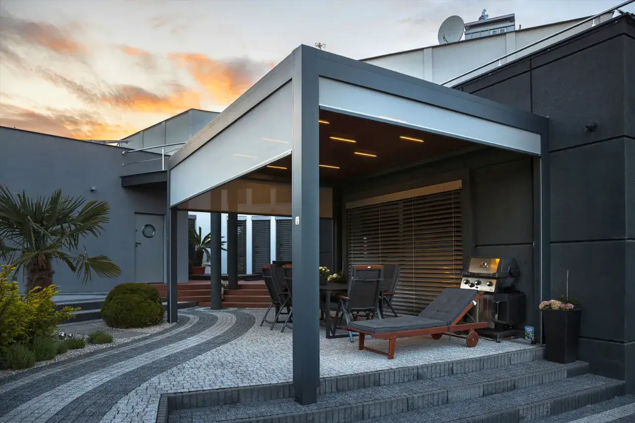 Nowoczesny taras z kostki na podwyższeniu, z grillem i miejscem do wypoczynku.